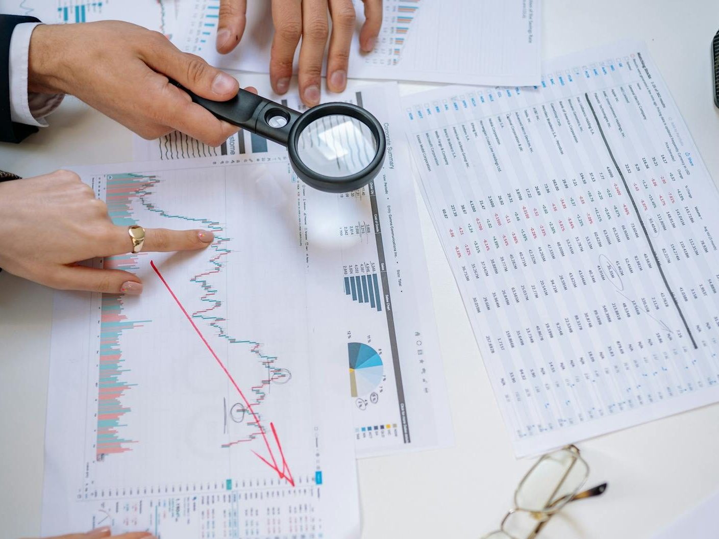 people hands around charts on table